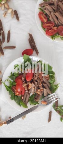 Buchweizen braune Pasta in weißen Schalen mit Tomaten, geräuchertem Lachs und Raketen Stockfoto