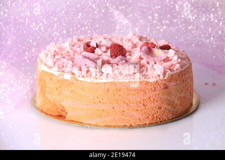 Ein rosa Kuchen mit Baiser bröckelt, Himbeeren, und zuckerhaltigen Rosenblätter. Stockfoto