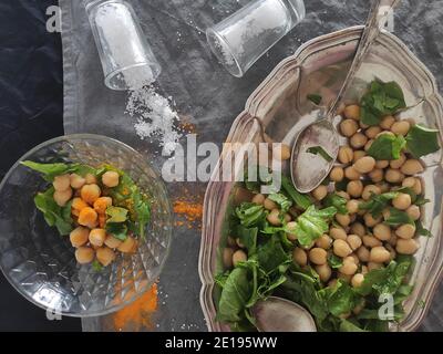 Kichererbsen und frischer Spinatsalat in einem silberovalen Tablett Stockfoto