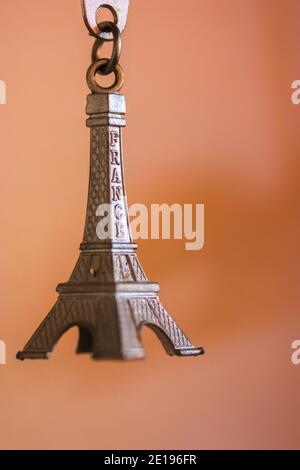 Schlüsselanhänger aus Metall in Form des Eiffelturms in Paris, Frankreich. Souvenir aus der Nahaufnahme auf orangefarbenem Hintergrund Stockfoto