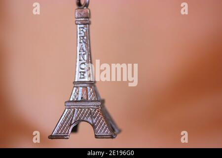 Schlüsselanhänger aus Metall in Form des Eiffelturms in Paris, Frankreich. Souvenir aus der Nahaufnahme auf orangefarbenem Hintergrund Stockfoto