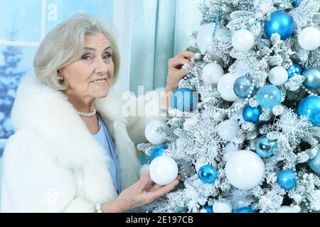 Glücklich lächelnde ältere Frau Dekoration Weihnachtsbaum Stockfoto