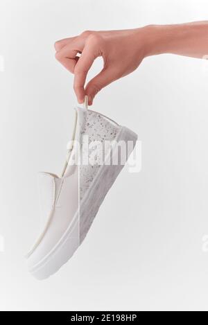 Hand hält einen weißen Lederslip-on-Schuh Stockfoto