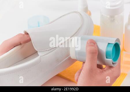 Entfernen von Schmutz von einem weißen Lederslipper mit der Hand Waschschwamm Stockfoto