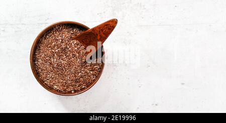 Kleine Holzschale voll Leinsamen - Linum usitatissimum - kleine Kugel innen, auf weißem Stein wie Schreibtisch, Blick von oben, Platz für Text r Stockfoto