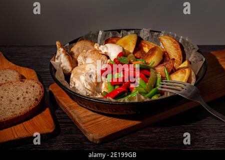 Gebackenes Huhn, Kartoffeln und Gemüse in einer gusseisernen Pfanne. Stockfoto