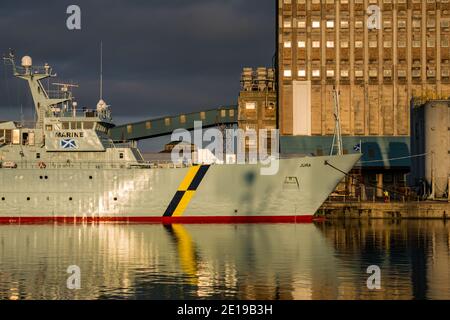 MPV Jura, Scottish Government Fisheries marine Protection ship & Industrial grain Silo with reflections, Imperial Dock, Leith, Edinburgh, Schottland, UK Stockfoto