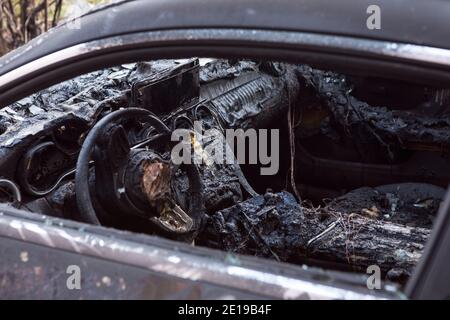 Nahaufnahme des verbrannten Autos. Lenkrad und Armaturenbrett. Auto nach dem Feuer. Brandstiftung. Unfall auf der Straße durch Geschwindigkeitsüberschreitung. Explosion. Stockfoto