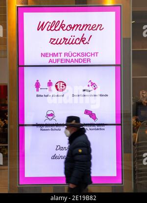 München, Deutschland. Januar 2021. Ein Mann geht durch die fast leere Innenstadt an einem Laden vorbei, der ein Schild im Fenster mit der Aufschrift "Willkommen zurück - kümmern Sie sich gegenseitig." Kredit: Peter Kneffel/dpa/Alamy Live Nachrichten Stockfoto