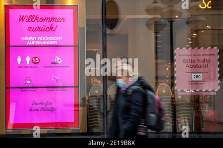 München, Deutschland. Januar 2021. Passanten gehen durch das fast leere Stadtzentrum an einem Laden vorbei, auf dem ein Schild mit der Aufschrift "Willkommen zurück - einander in Betracht ziehen" steht. Kredit: Peter Kneffel/dpa/Alamy Live Nachrichten Stockfoto