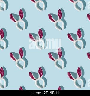 Ostermuster aus rosa und weißen Hasenohren auf blauem Hintergrund, Draufsicht, starke Schatten Stockfoto