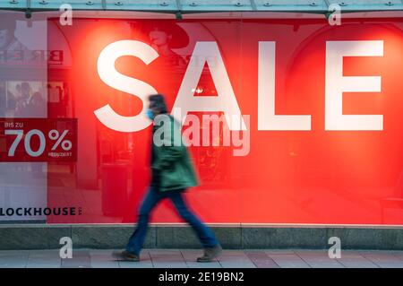 München, Deutschland. Januar 2021. Ein Mann geht durch die fast leere Innenstadt, vorbei an einem Laden mit dem Wort "Sale" hängt im Fenster. Kredit: Peter Kneffel/dpa/Alamy Live Nachrichten Stockfoto