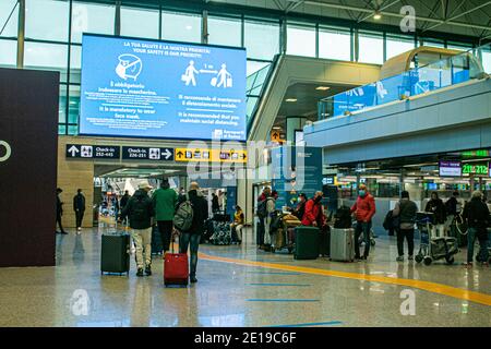 ROM FIUMICINO, ITALIEN 5. JANUAR 2021. Passagiere warten auf den Check-in unter einem großen Gesundheitswarnschild, weil sie Schutzmasken tragen und soziale Distanzierung aufrechterhalten. Nur wenige Passagiere reisen während der nationalen Sperre am Flughafen Rom Fiuminico an. Die italienische Regierung hat kürzlich Flüge aus dem Vereinigten Königreich verboten, nachdem ein neuer Coronavirus-Mutant-Stamm entdeckt wurde. Kredit: amer ghazzal/Alamy Live Nachrichten Stockfoto