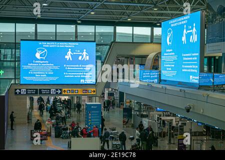 ROM FIUMICINO, ITALIEN 5. JANUAR 2021. Passagiere warten auf den Check-in unter einem großen Gesundheitswarnschild, weil sie Schutzmasken tragen und soziale Distanzierung aufrechterhalten. Nur wenige Passagiere reisen während der nationalen Sperre am Flughafen Rom Fiuminico an. Die italienische Regierung hat kürzlich Flüge aus dem Vereinigten Königreich verboten, nachdem ein neuer Coronavirus-Mutant-Stamm entdeckt wurde. Kredit: amer ghazzal/Alamy Live Nachrichten Stockfoto