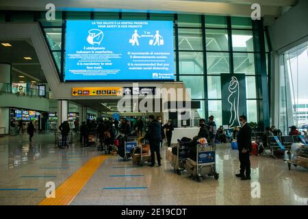 ROM FIUMICINO, ITALIEN 5. JANUAR 2021. Passagiere warten auf den Check-in unter einem großen Gesundheitswarnschild, weil sie Schutzmasken tragen und soziale Distanzierung aufrechterhalten. Nur wenige Passagiere reisen während der nationalen Sperre am Flughafen Rom Fiuminico an. Die italienische Regierung hat kürzlich Flüge aus dem Vereinigten Königreich verboten, nachdem ein neuer Coronavirus-Mutant-Stamm entdeckt wurde. Kredit: amer ghazzal/Alamy Live Nachrichten Stockfoto