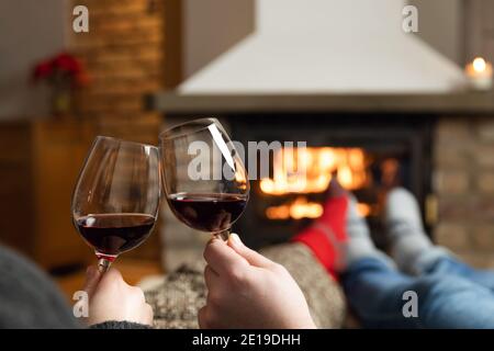 Verliebte Paare sitzen in einem gemütlichen Zimmer mit Kamin auf einem Sofa mit einem Glas Wein. Familie und Liebe Konzept. Stockfoto