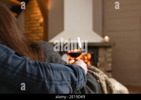 Verliebte Paare sitzen in einem gemütlichen Zimmer mit Kamin auf einem Sofa mit einem Glas Wein. Familie und Liebe Konzept. Stockfoto