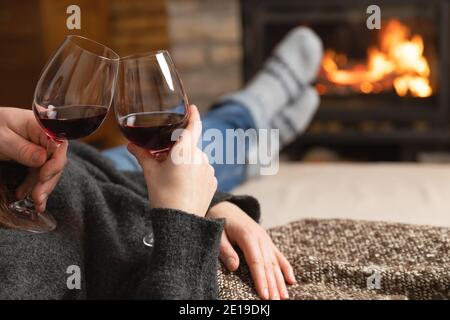 Verliebte Paare sitzen in einem gemütlichen Zimmer mit Kamin auf einem Sofa mit einem Glas Wein. Familie und Liebe Konzept. Stockfoto