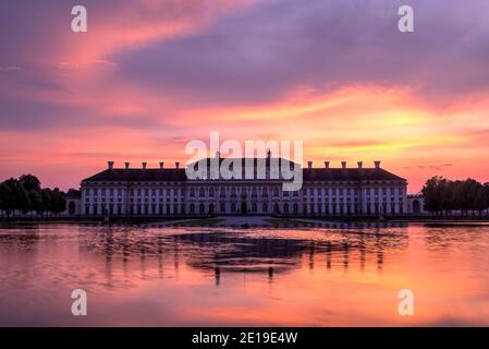 Das Schloss Schleißheim in der Abenddämmerung mit einem dramatischen feurigen Himmel gesehen und reflektiert in den Garten Brunnen. Foto aufgenommen am 25. August 2019 in Oberschleis Stockfoto