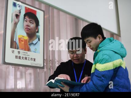 (210105) -- CHONGQING, 5. Januar 2021 (Xinhua) -- Liang Pan (L) spricht mit dem stellvertretenden Trainer Hu Jilong auf einer Trainingsbasis für den WorldSkills Wettbewerb an der Chongqing Technician College of Railway Transportation im südwestlichen China Chongqing, 30. Dezember 2020. Liang Pan, der einst die Abitur nicht bestanden hatte, ist heute Lehrer am Chongqing Technician College of Railway Transportation. Von einem Berufsschüler, einem Laien in der Elektronik bis hin zu einem Experten und Weltmeister brauchte Liang Pan 6 Jahre, um sich den Traum zu erfüllen. Die Berufserfahrung in einem sehr jungen Alter ma Stockfoto