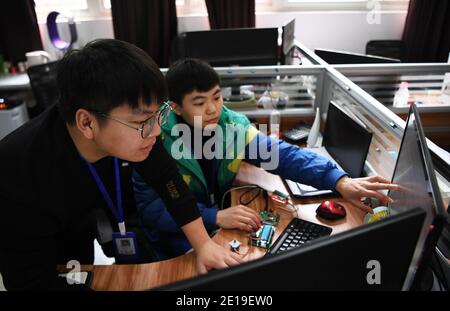 (210105) -- CHONGQING, 5. Januar 2021 (Xinhua) -- Liang Pan (L) und der stellvertretende Trainer Hu Jilong diskutieren den Trainingsplan auf einer Trainingsbasis für den WorldSkills Wettbewerb am Chongqing Technician College of Railway Transportation im südwestlichen chinesischen Chongqing, 30. Dezember 2020. Liang Pan, der einst die Abitur nicht bestanden hatte, ist heute Lehrer am Chongqing Technician College of Railway Transportation. Von einem Berufsschüler, einem Laien in der Elektronik bis hin zu einem Experten und Weltmeister brauchte Liang Pan 6 Jahre, um sich den Traum zu erfüllen. Die Arbeitserfahrungen bei Stockfoto