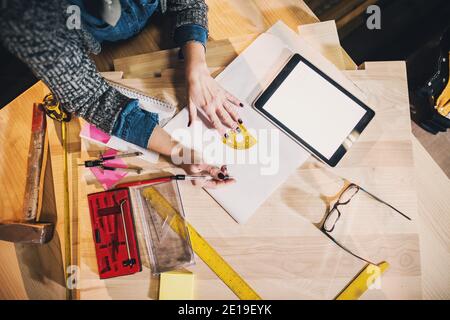 Draufsicht auf Werkzeuge und Papiere und Tablet in der Werkstatt. Frau Business Top View Konzept Stockfoto