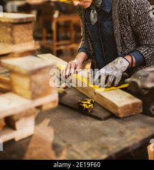 Nahaufnahme der fleißige konzentrierte professionelle ernsthafte Schreiner Frau Halten Lineal und Bleistift, während Marken auf dem Holz Am Tisch im Stockfoto