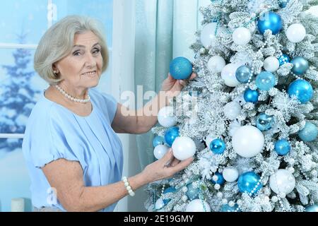 Glücklich lächelnde ältere Frau Dekoration Weihnachtsbaum Stockfoto