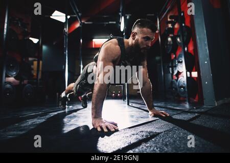 Sportliche Form Bodybuilder Kerl in militärische Weste tun Liegestütze Übung in der Turnhalle. Stockfoto