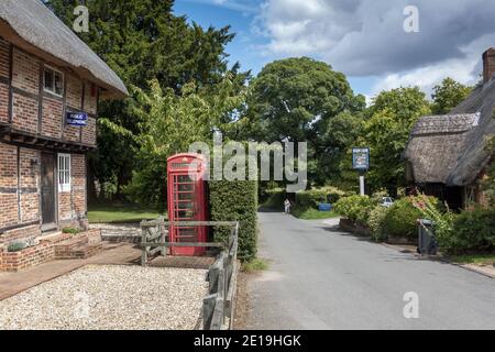 Reethaus mit roter Telefonbox und der Tichborne Arms Pub im charmanten Dorf Tichborne, Hampshire, England, Großbritannien Stockfoto