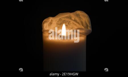 Beleuchtete Kerze in der Dunkelheit (zentriert) für ein warmes und friedliches Ambiente Stockfoto