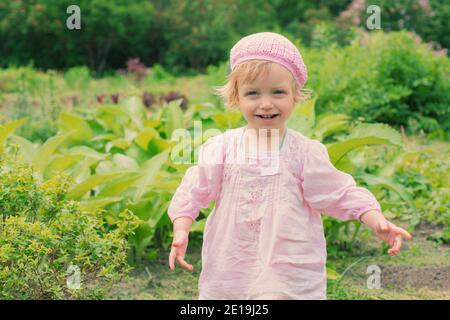 Kleines Mädchen geht im Sommer im Garten Stockfoto