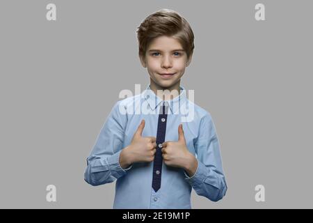 Kind Junge gibt Daumen nach oben vor grauem Hintergrund. Stockfoto