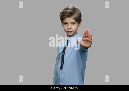 Kleiner Junge mit Stop-Geste auf grauem Hintergrund. Stockfoto