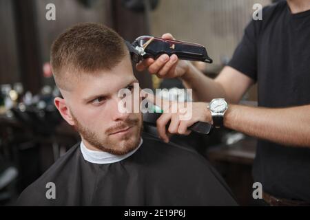 Nahaufnahme eines jungen attraktiven Mannes, der neue Frisur bekommt Im Friseurladen Stockfoto