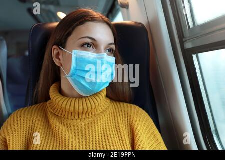 Nahaufnahme der weiblichen Pendler mit chirurgischen Gesichtsmaske Blick durch Zug Fenster. Zug Passagier mit Schutzmaske Reisen sitzen in Business cla Stockfoto