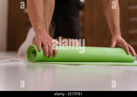 Abwickelrolle Matte, Vorbereitung eines Platzes für Sport Fitness Mann. Entschlossener Kerl, der körperliches Training macht. Starker, hübscher junger Mann, ein Fitnessstudio Stockfoto