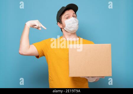Lieferer hält Kartons in medizinischen Gummihandschuhen und Maske. Online-Shopping und Express-Lieferung unter Quarantäne Stockfoto
