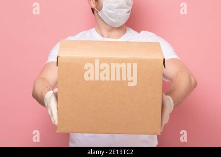 Delivery Mann hält Karton in medizinischen Gummihandschuhe und Maske. Online-Shopping und Express-Lieferung . Quarantäne Stockfoto