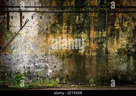Gealterte Betonwandstruktur. Alte strukturierte Zement Grunge Wandoberfläche Hintergrundmuster mit Rissen, Kratzern, Moos und Flecken. Stockfoto
