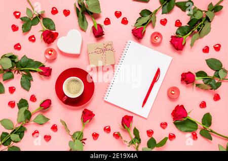 Schreiben fordert zum Valentinstag. Flache Lay mit roten Rosen, Kaffeetasse, Geschenk, Herzen und leeres Notizbuch auf rosa Hintergrund. Sei mein Valentinstag Stockfoto