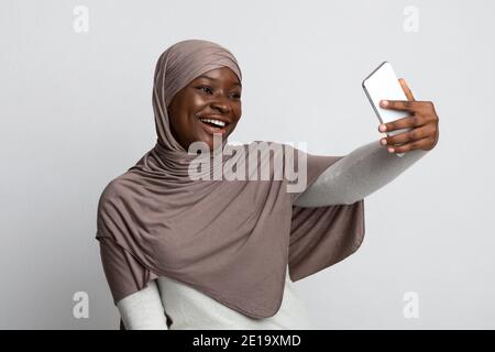 Fröhliche Schwarze Muslimische Dame In Hijab Nimmt Selfie Auf Smartphone Stockfoto