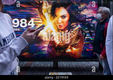 Hongkong, China. Dezember 2020. Fußgänger mit Masken gehen an einer Werbetafel von Warner Bros Official Site und DC Comics-Charakter Wonder Woman 1984 Film in Hong Kong vorbei. Kredit: Budrul Chukrut/SOPA Images/ZUMA Wire/Alamy Live Nachrichten Stockfoto