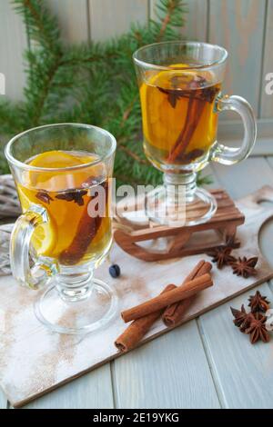 Heißer Tee im Glas mit Gewürzen auf Holzhintergrund. Stillleben, Saison- und Urlaubskonzept. Vertikales Bild Stockfoto