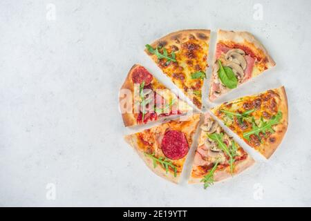 Pizza-Party-Konzept. Set von Pizzen mit verschiedenen Füllungen, Stücke von verschiedenen Pizza, Glas und Flasche mit Wein. Flatlay Draufsicht Kopieplatz auf weiß Stockfoto