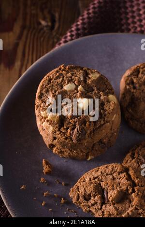 Dreifache Schokolade Chip Cookies mit Stücken von weißer Milch und Dunkle Schokolade mit dunkler kreativer Beleuchtung Stockfoto