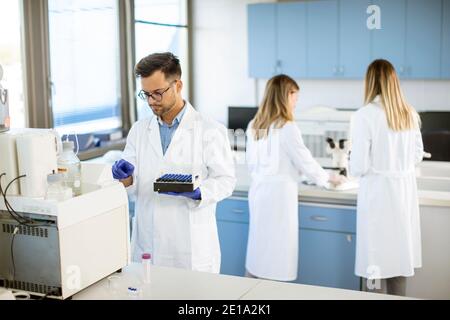 Handsome Forscher in schützende Arbeitskleidung stehen im Labor und Analyse von flüssigen Proben Stockfoto