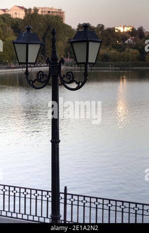 Ein dunkles Straßenlicht im Vintage-Stil auf dem See. Dies wird bei Sonnenuntergang fotografiert. Stockfoto