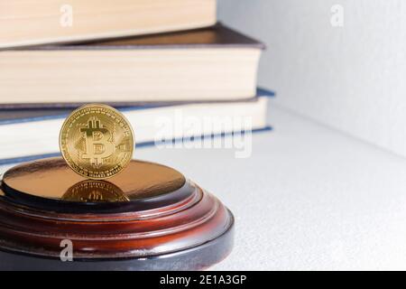 Einzelne Bitcoin Münze oder Symbol steht in scharfem Fokus auf einer reflektierenden Oberfläche mit Gold gefärbt. Stockfoto