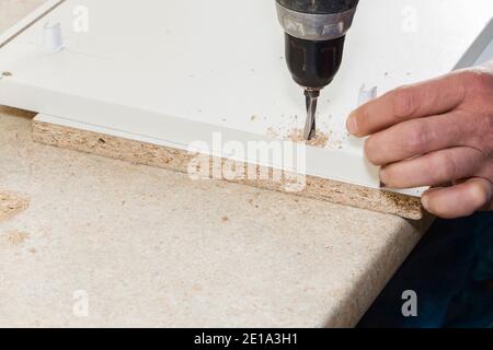 Arbeiter bohrt beim Zusammenbau von Möbeln ein Loch. Stockfoto